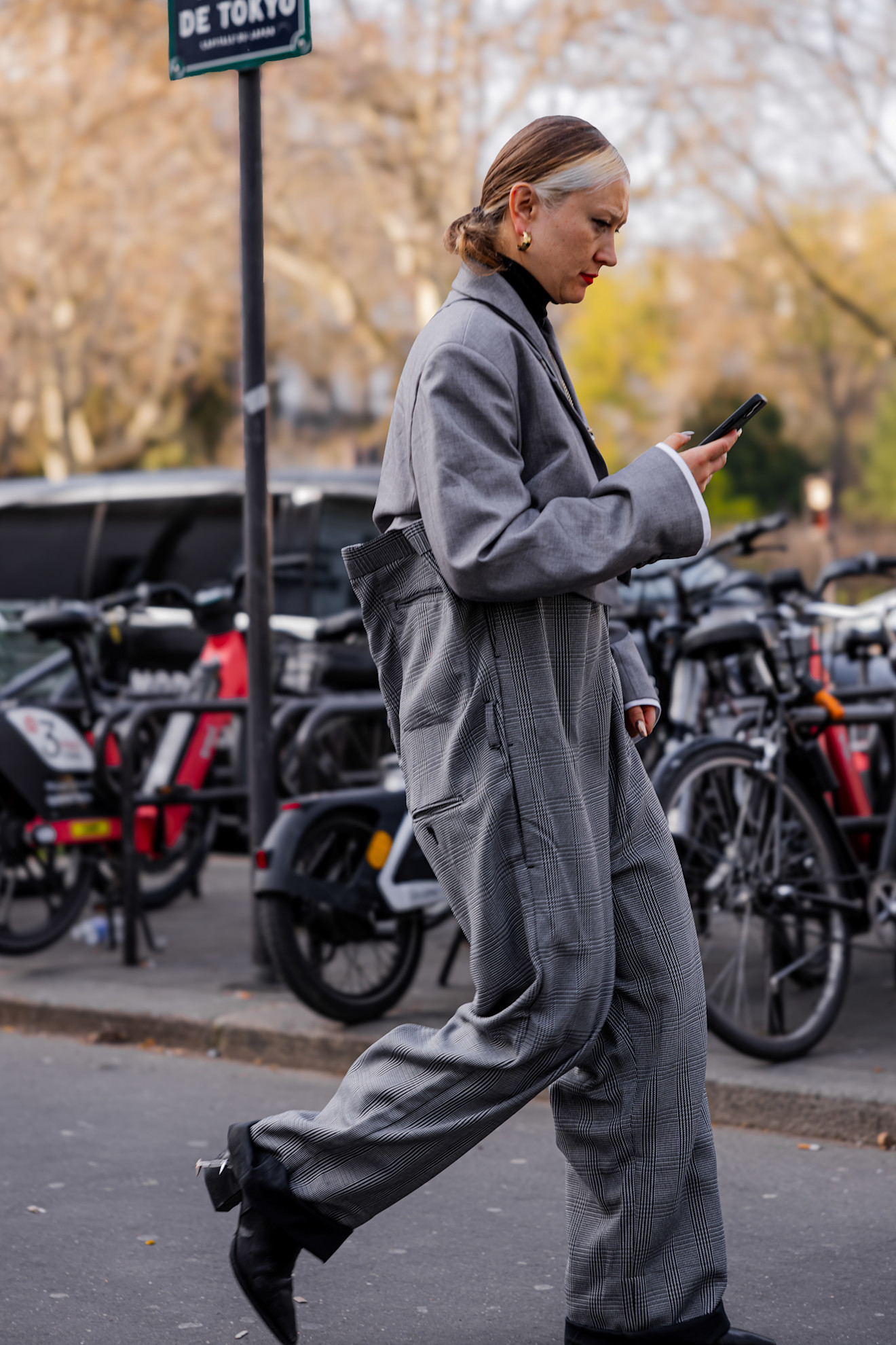 a woman in a gray suit, black boots with a low ponytail in front of bikes