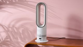 The Dyson Hot and Cool HF1 is sitting on a coffee table in a pink living room. 