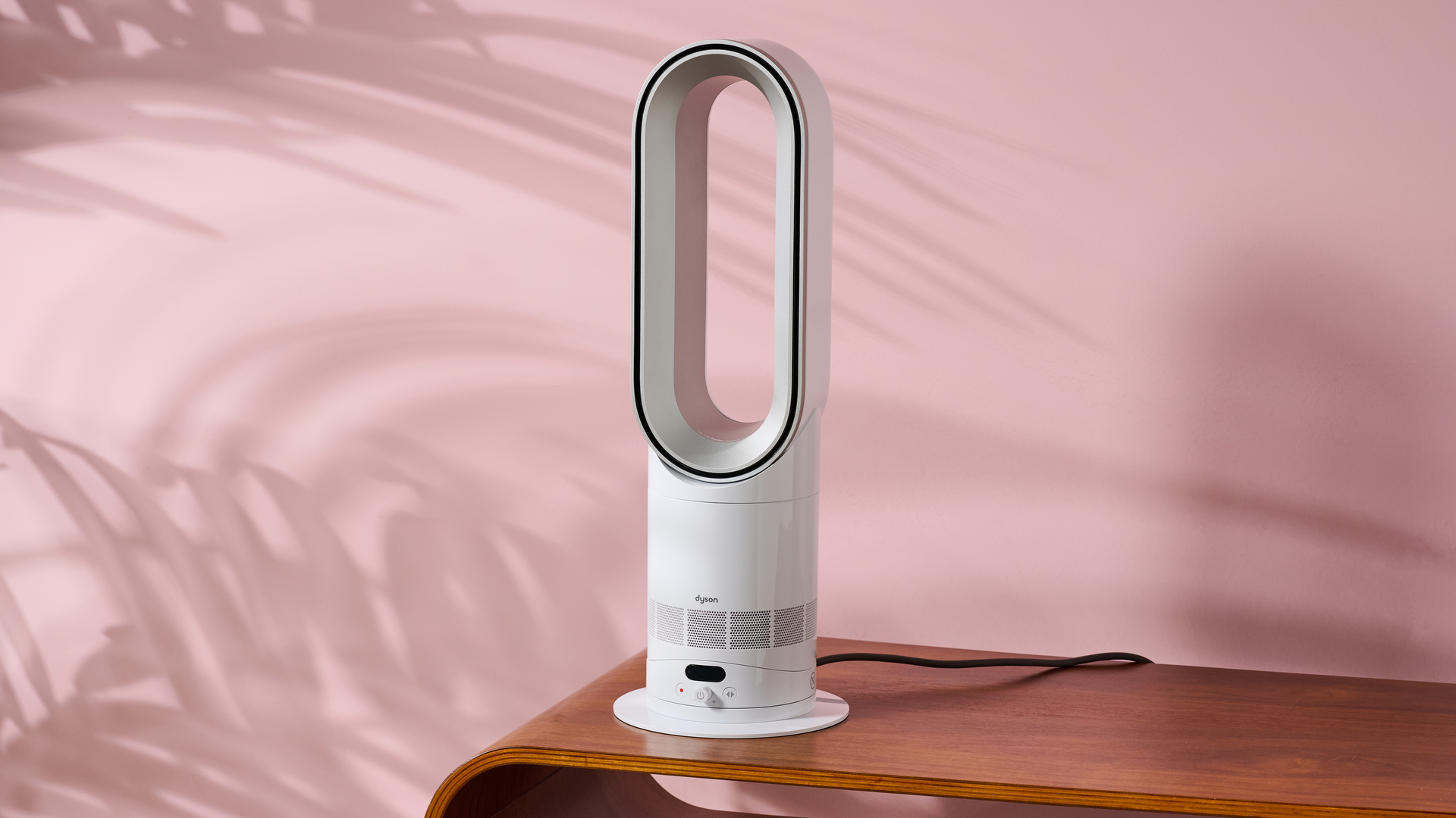 The Dyson Hot and Cool HF1 is sitting on a coffee table in a pink living room. 