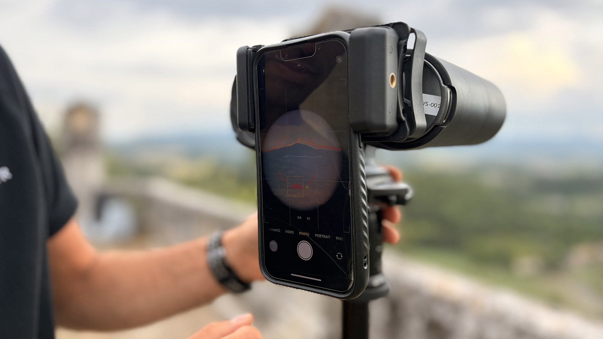 A phone is attached to the eyepiece of a pair of binoculars 