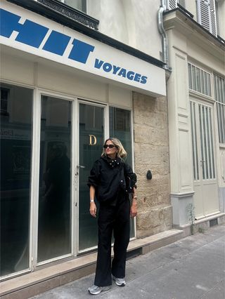 Eliza Huber trägt in Paris eine schwarze sportliche Jacke von Proenza Schouler mit einem roten Tanktop, schwarzen Popeline-Hosen und grauen New Balance-Sneakern.