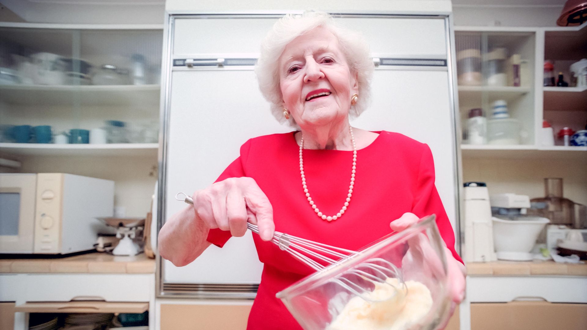 Marguerite Patten whisks cake mixture in a glass bowl