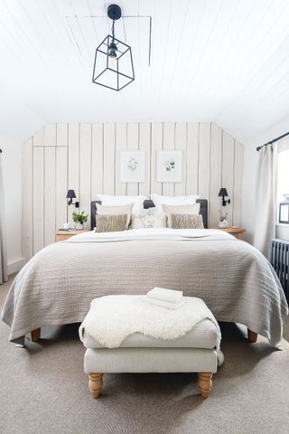 loft bedroom with tongue and groove paneling behind double bed with pale pink colors