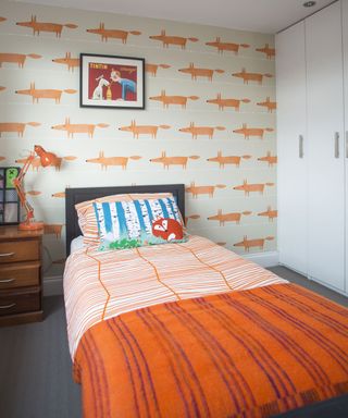 kids bedroom with orange fox printed white wall and white cupboard