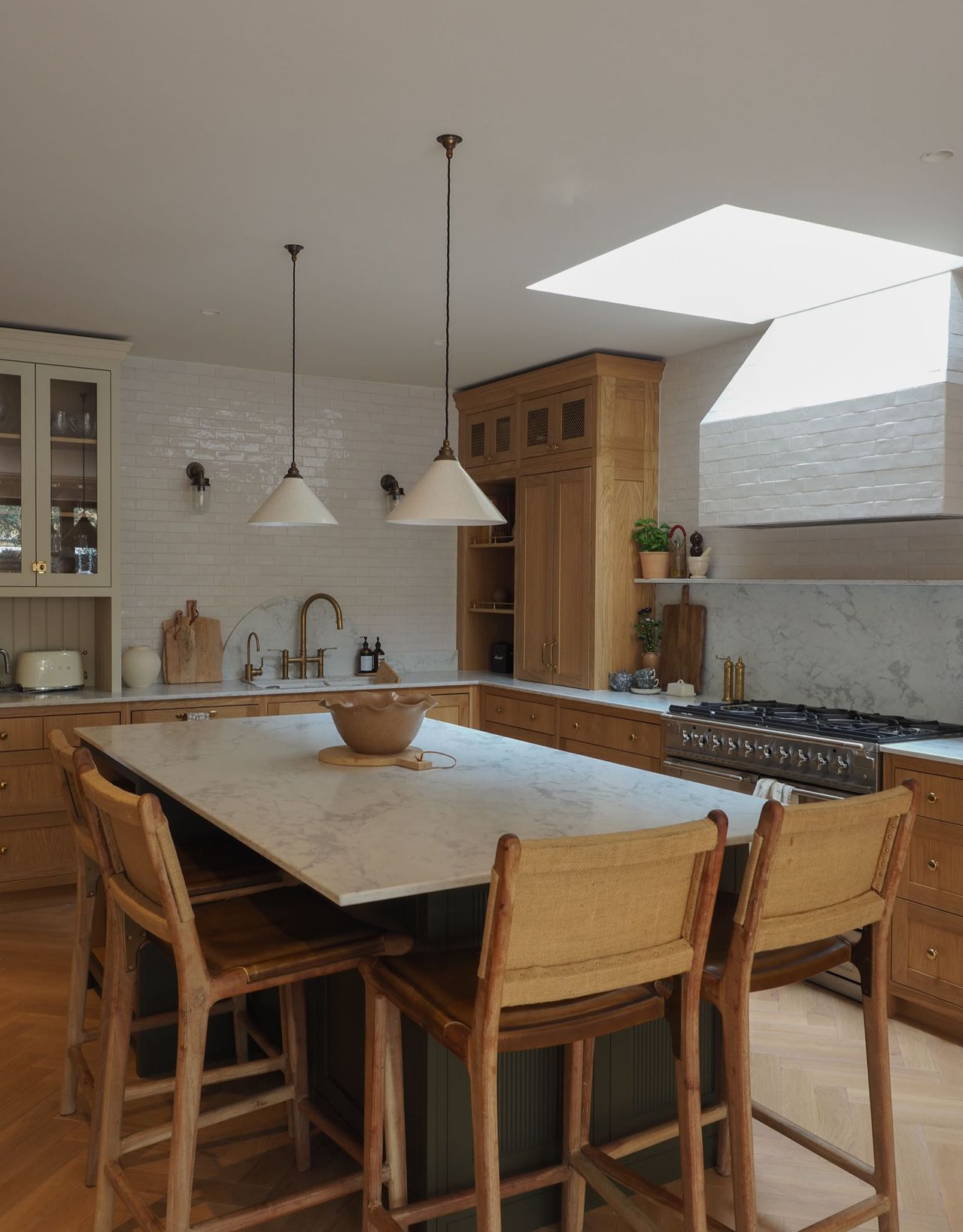 A modern kitchen with kitchen island seating with wooden bar stools and two pendant lights hanging over the island in a wood and white themed space