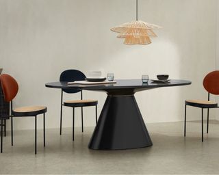 Rumana 6 Seat Oval Dining Table in black, in the middle of a dining room with black and red chairs surrounding