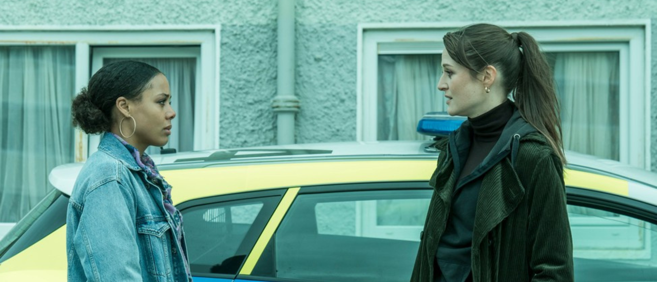 Image of two women in front of a police car