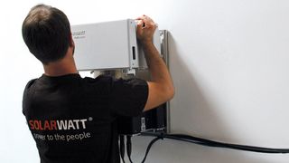men installing white solar battery system onto wall