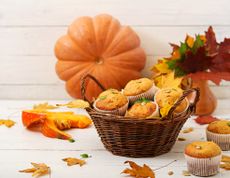 Pumpkin pecan muffins in a basket with pumpkin displayed behind
