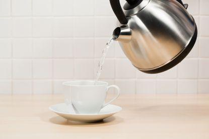 Water pouring from a kettle into tea cup