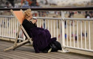 A woman cosies up in her deckchair with a blanket and a hot driink on Bournemouth Pier