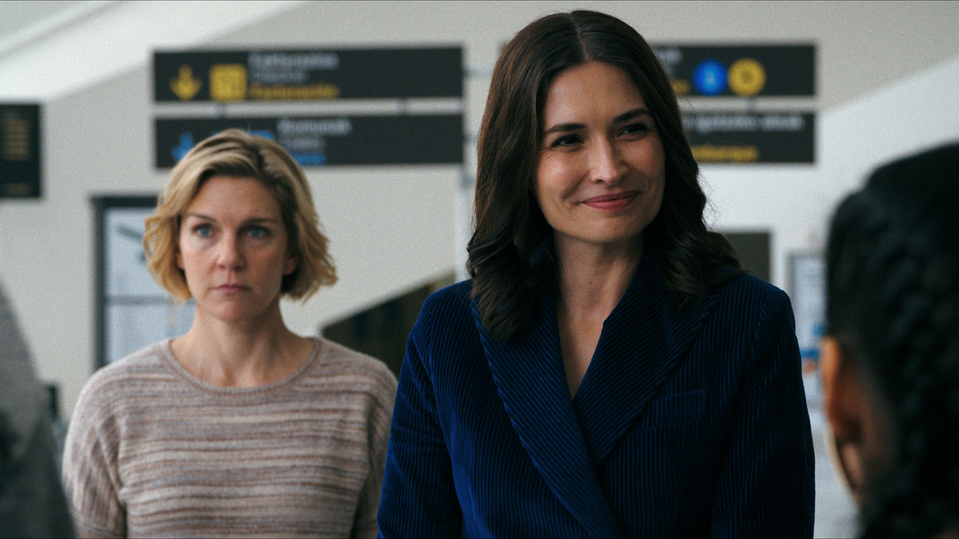 Carol standing behind a smiling Zosia in Pluribus episode 2