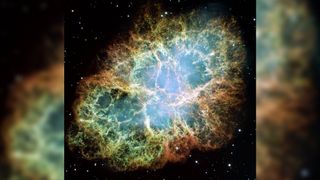 crab nebula made of large filaments of gas and dust colored orange, red, blue and green.
