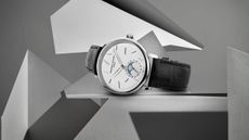 Lifestyle image of the Frederique Constant Slimline Moonphase Date Manufacture on its side sitting on a grey podium