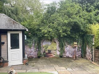 A garden wall covered with a shower curtain depicting the view down a garden path with lush greenery