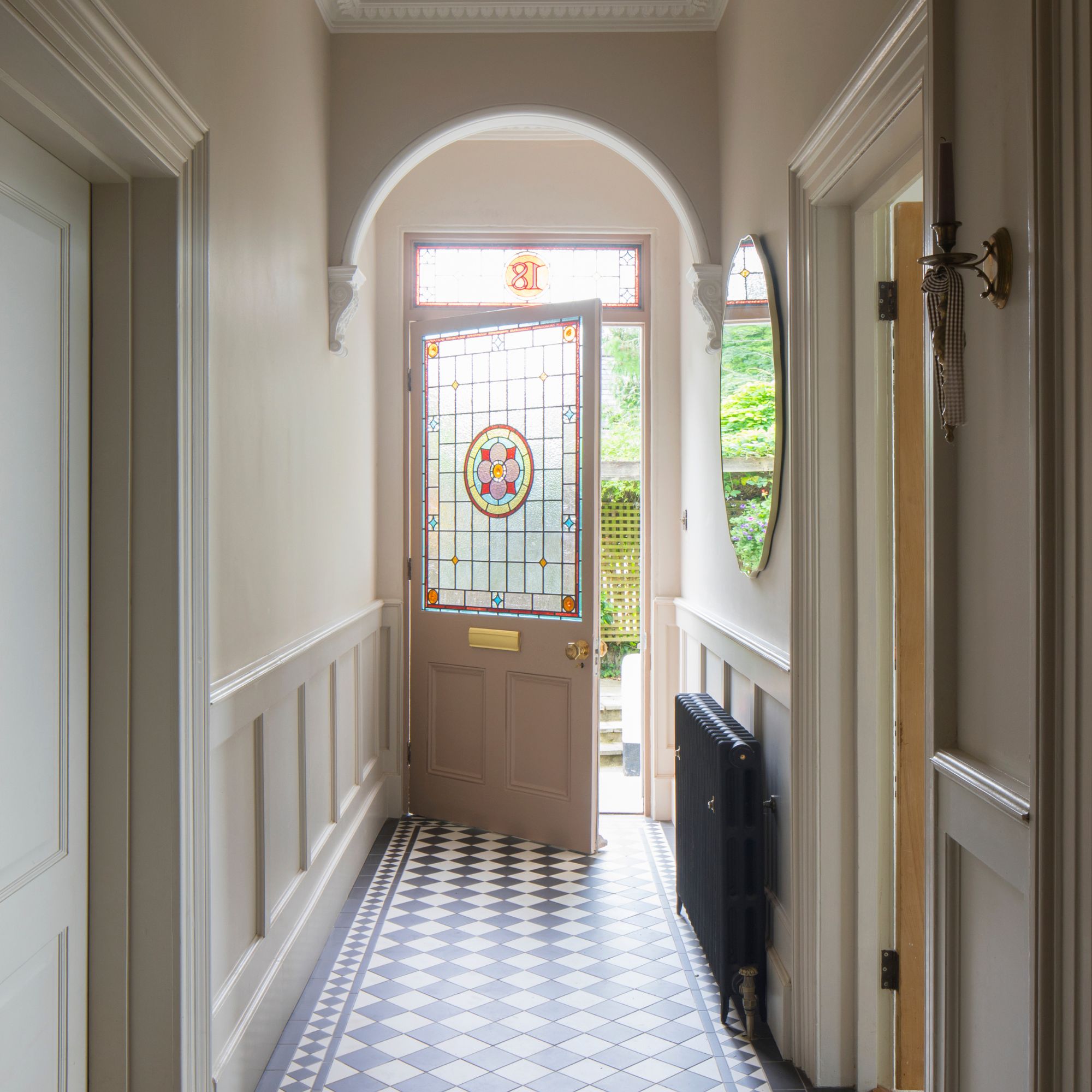 characterful hallway with a stained glass front door and black and white checkered tiles on the floor