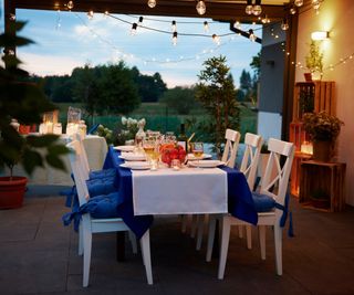 Festoon lights on a porch over a table set for dinner