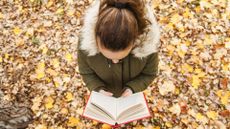 Girl reading a book in the autumn leaves