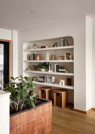 Plants scattered around a modern home with wooden stools and open shelving