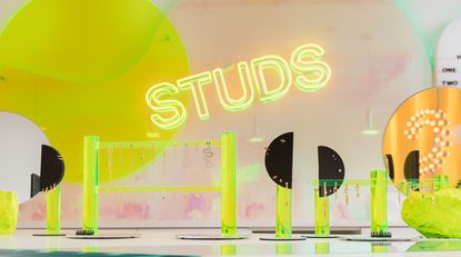 Studs written in neon with earrings on display around it