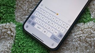 iPhone 15 Pro Max keyboard on a green and white chequered background