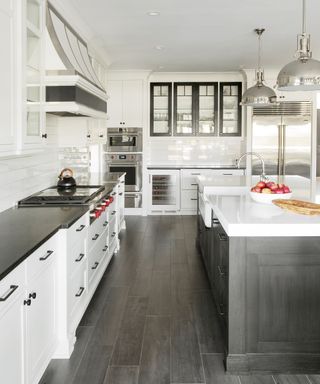 A white kitchen with black worktops and a black island