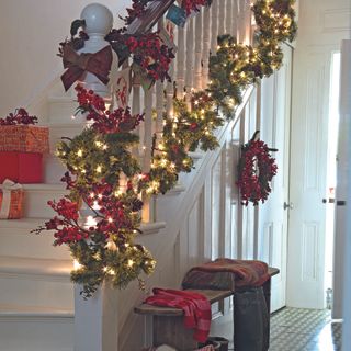 Hallway and staircase with traditional green and red Christmas decorations and garland.
