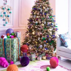 Colorfully decorated Christmas tree and gifts in white living room 