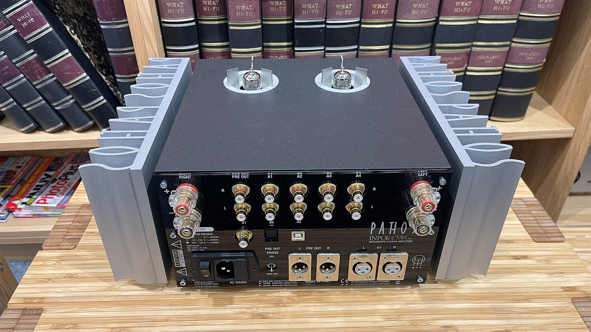 Pathos Inpol Remix MkII integrated amplifier on wooden hi-fi rack in front of bookcase showing rear connections