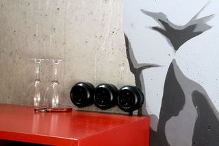 A red table with two upturned wine glasses and a red-handled utensil. A grey design has been painted on the wall