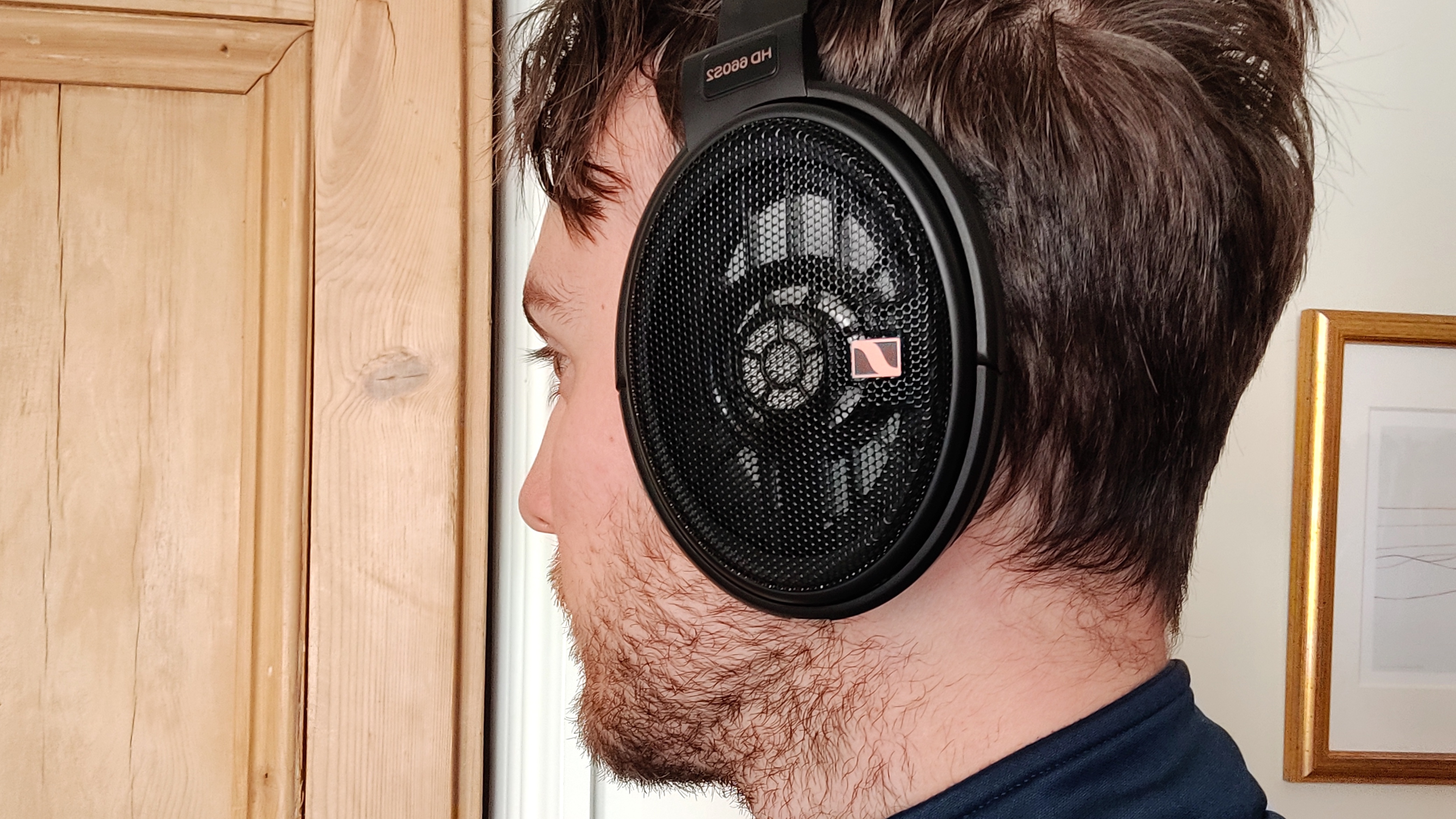 A member of the TechRadar team wearing the Sennheiser HD-660S2 headphones in front of a wooden door.