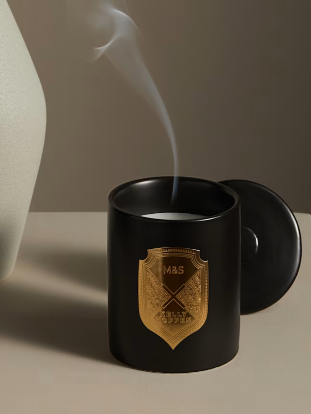 A black ceramic candle with a gold crest and a lid from M&amp;amp;S x Kelly Hoppen