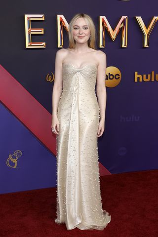 Dakota Fanning on the 2024 Emmys red carpet wearing a gold dress