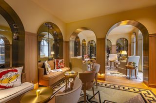 A cream communal hotel area with arched doorways and eclectic furniture and rugs