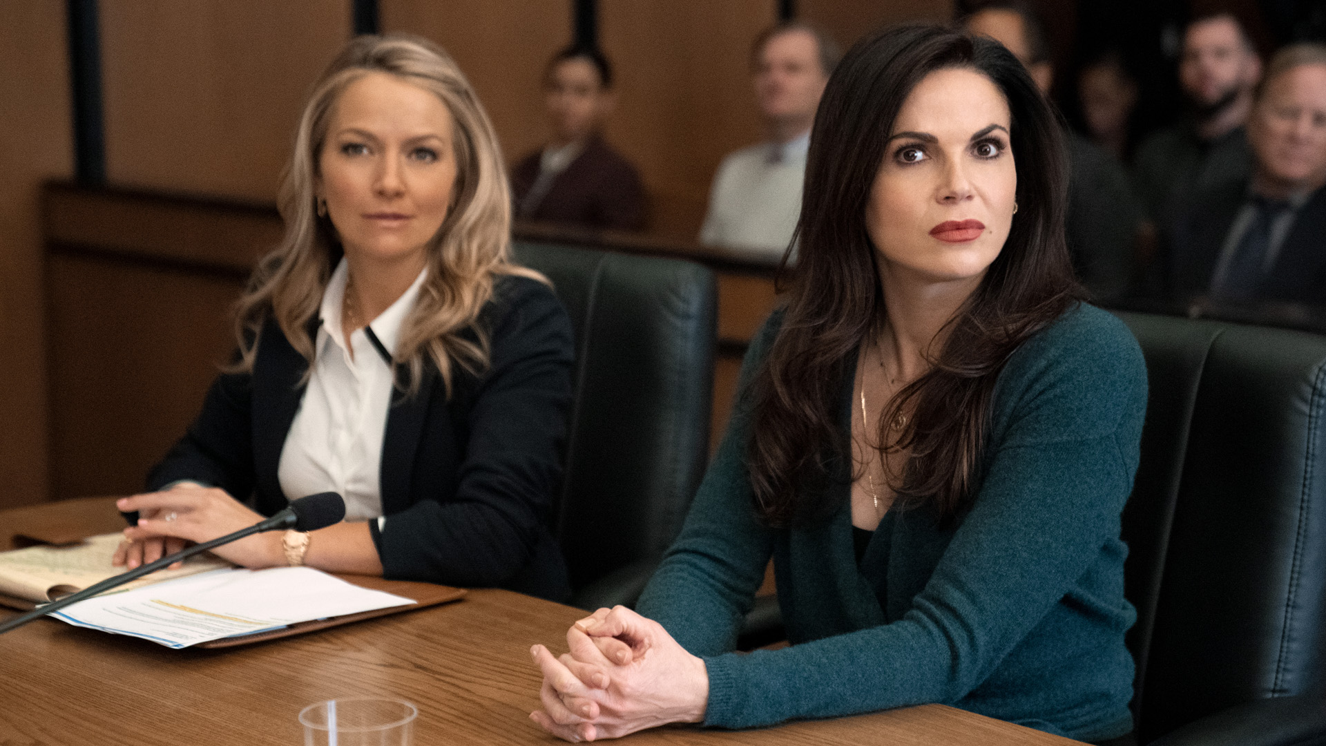 Lorna and Lisa sit in a courtroom as they look at someone off-camera in The Lincoln Lawyer season 2