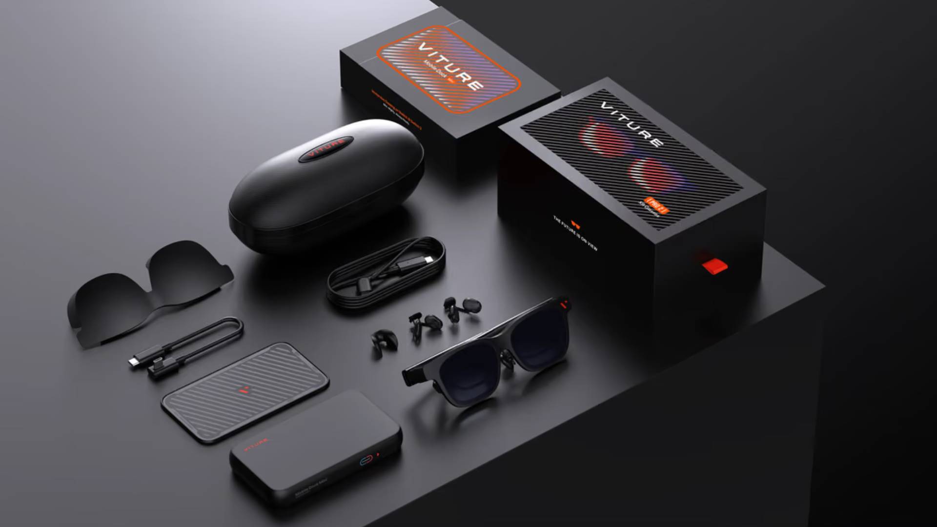 Official marketing image showing the Viture Pro 2 glasses and its accessories on a black table.