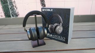 Noble FoKus Apollo on a headphone stand, next to the retail packaging