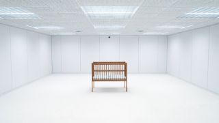 A wooden crib standing in the middle of a white room in Severance season 2 episode 10