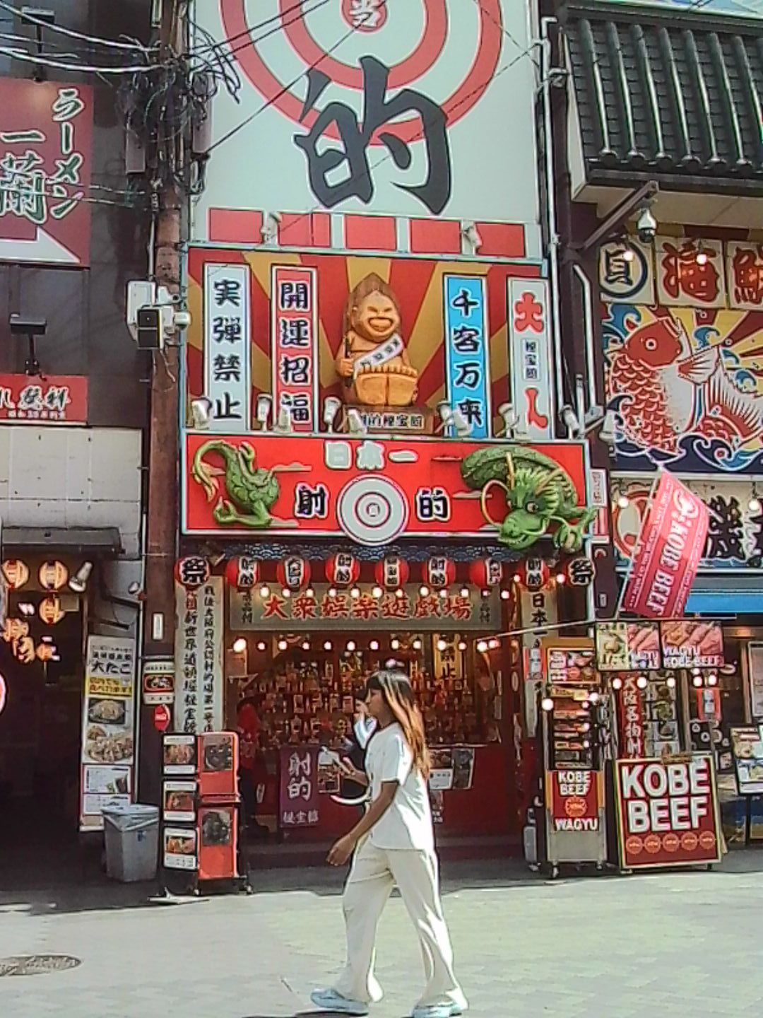 Brightly colored Japanese storefront with bold signage and a pedestrian walking past.