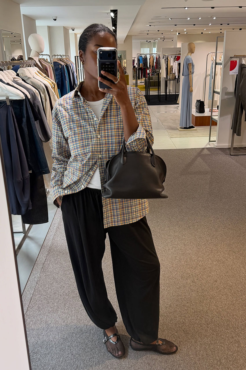 A woman wearing plaid button-down, black pants, and mesh flats.
