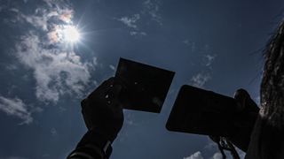A man use protective mirror to watch solar eclipse in Palembang, Indonesia on April 20, 2023