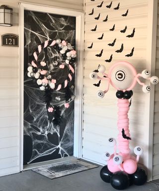 Halloween door decor idea with webbed door effect and balloon wreath and balloon alien figure