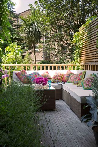 bohemian garden ideas: corner sofa on decking with colourful cushions
