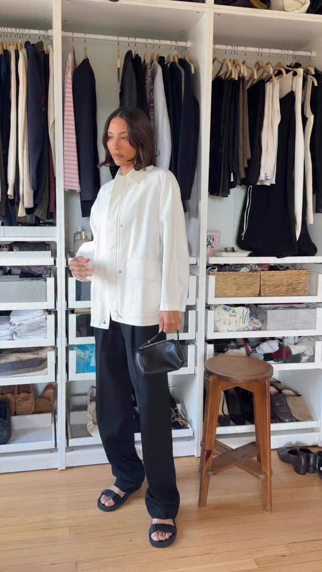 Woman in a white jacket, black pants, and chunky sandals.