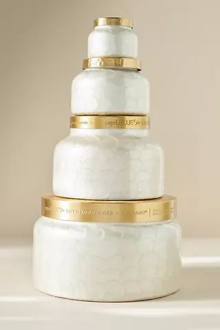 Four pearlescent round jars with gold lids stacked vertically with the widest one at the bottom 