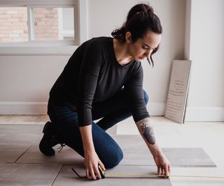 Woman with dark hair and tattoo laying white floor tile