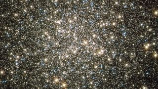 A mass of gold and blue stars are pictured shining against the blackness of space.