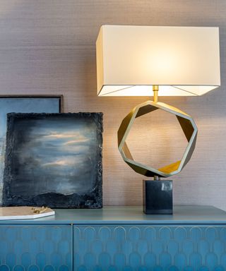Lamp and artwork against blue wallpaper