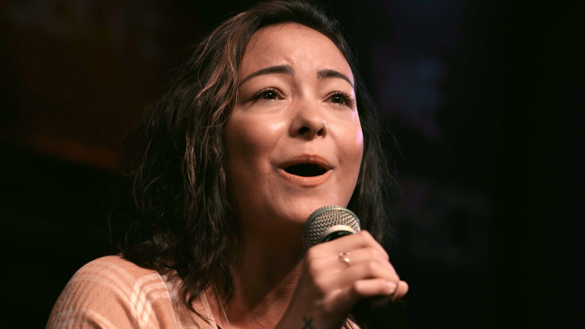 A close up of Mica Miller singing into a microphone in Death of a Pastor's Wife.