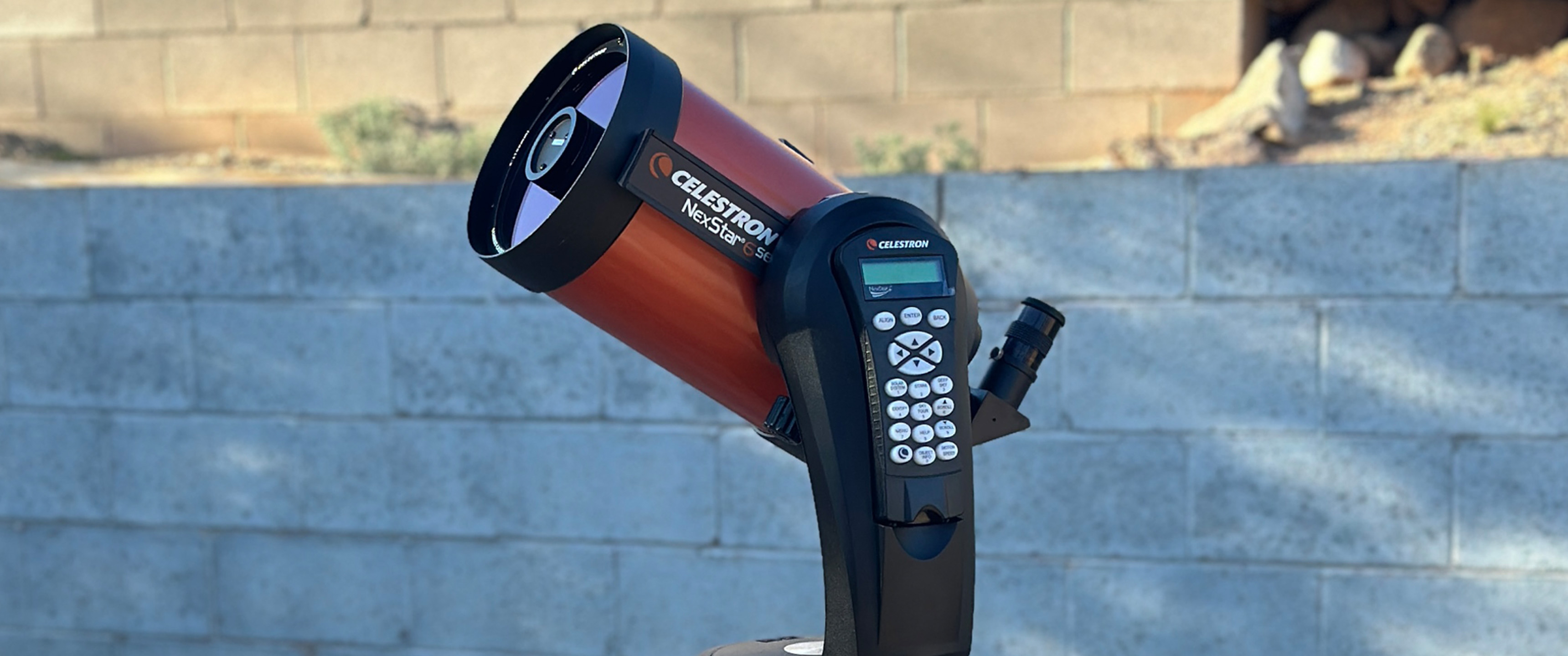 Celestron NexStar 6SE in a backyard, in front of a grey brick wall